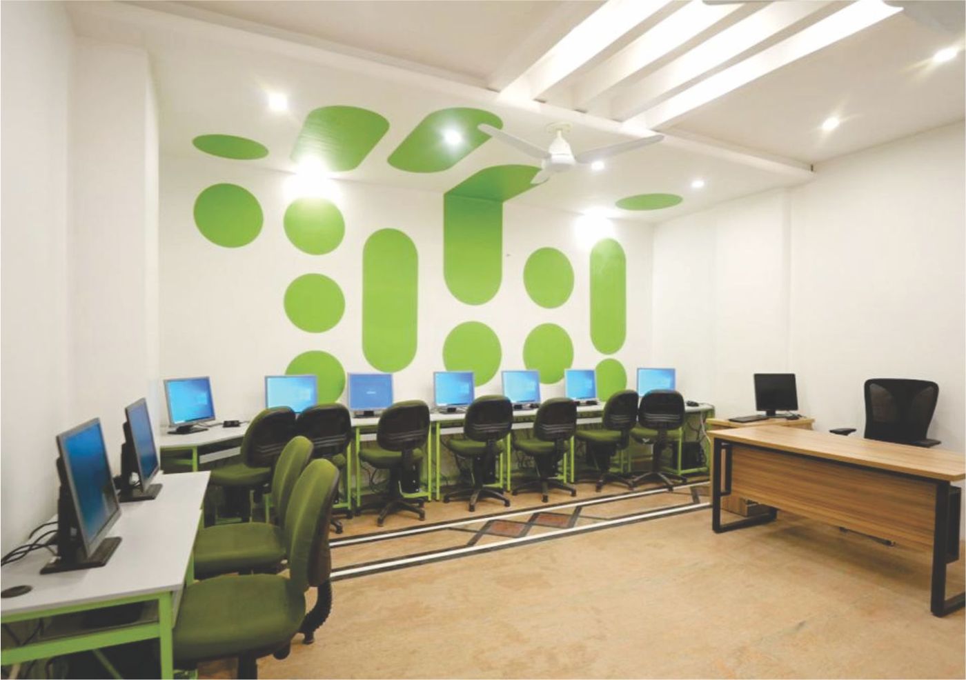 The London School computer lab with modern workstations and green-dot feature wall
