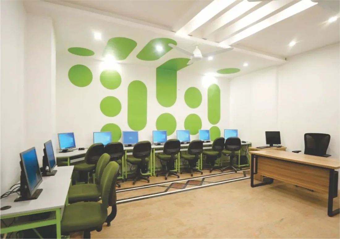 London School computer lab with workstations and green-dot feature wall