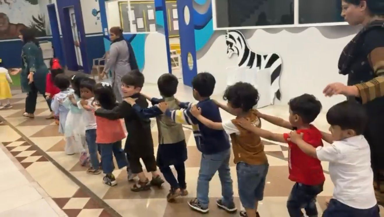 Nursery children holding hands through the corridor